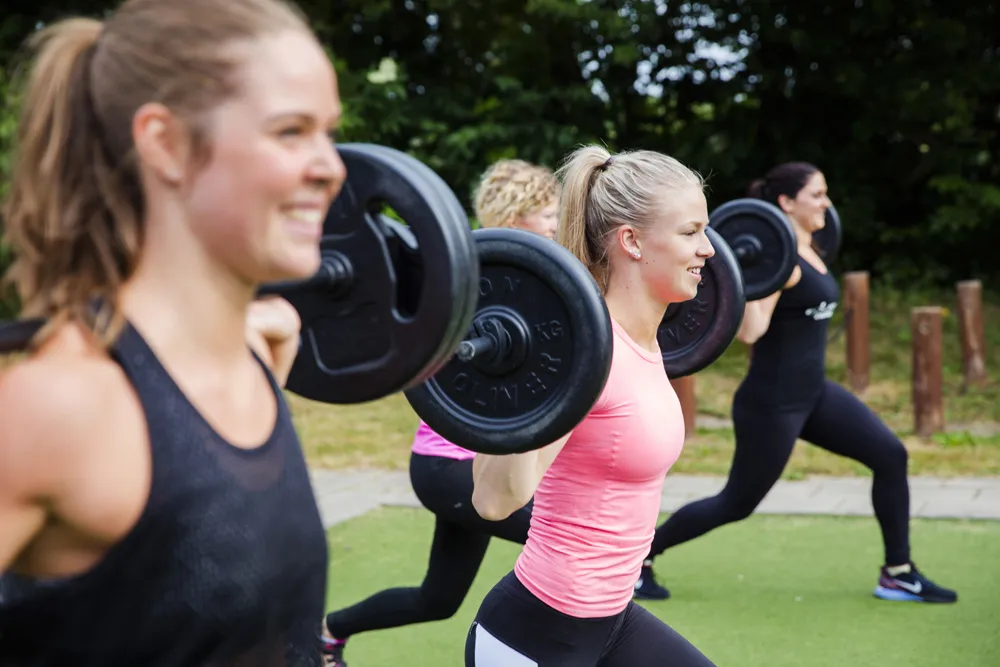 kvinnor tränar med viktstång utomhus tillsammans