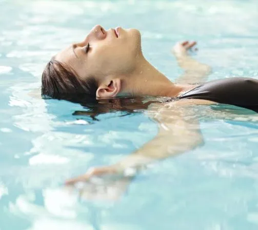 kvinna som ligger avslappnat i en pool och blundar