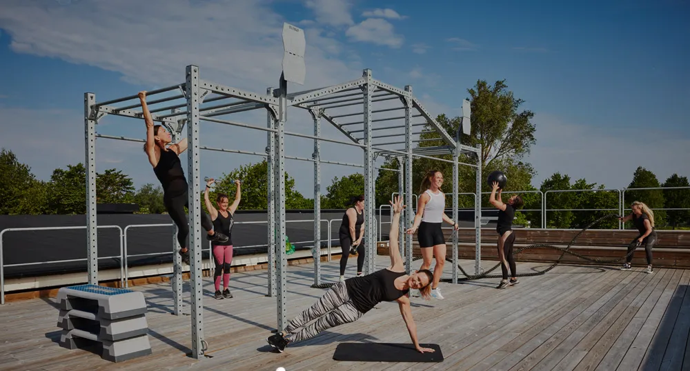 En grupp kvinnor tränar på ett utegym i soligt väder