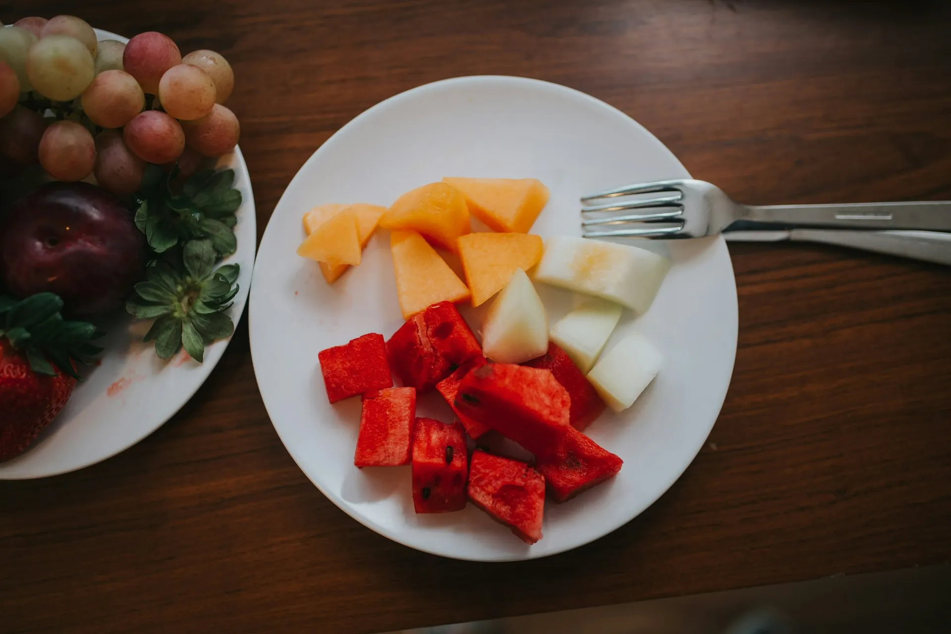 skivad vattenmelon och mango på tallrik med gaffel